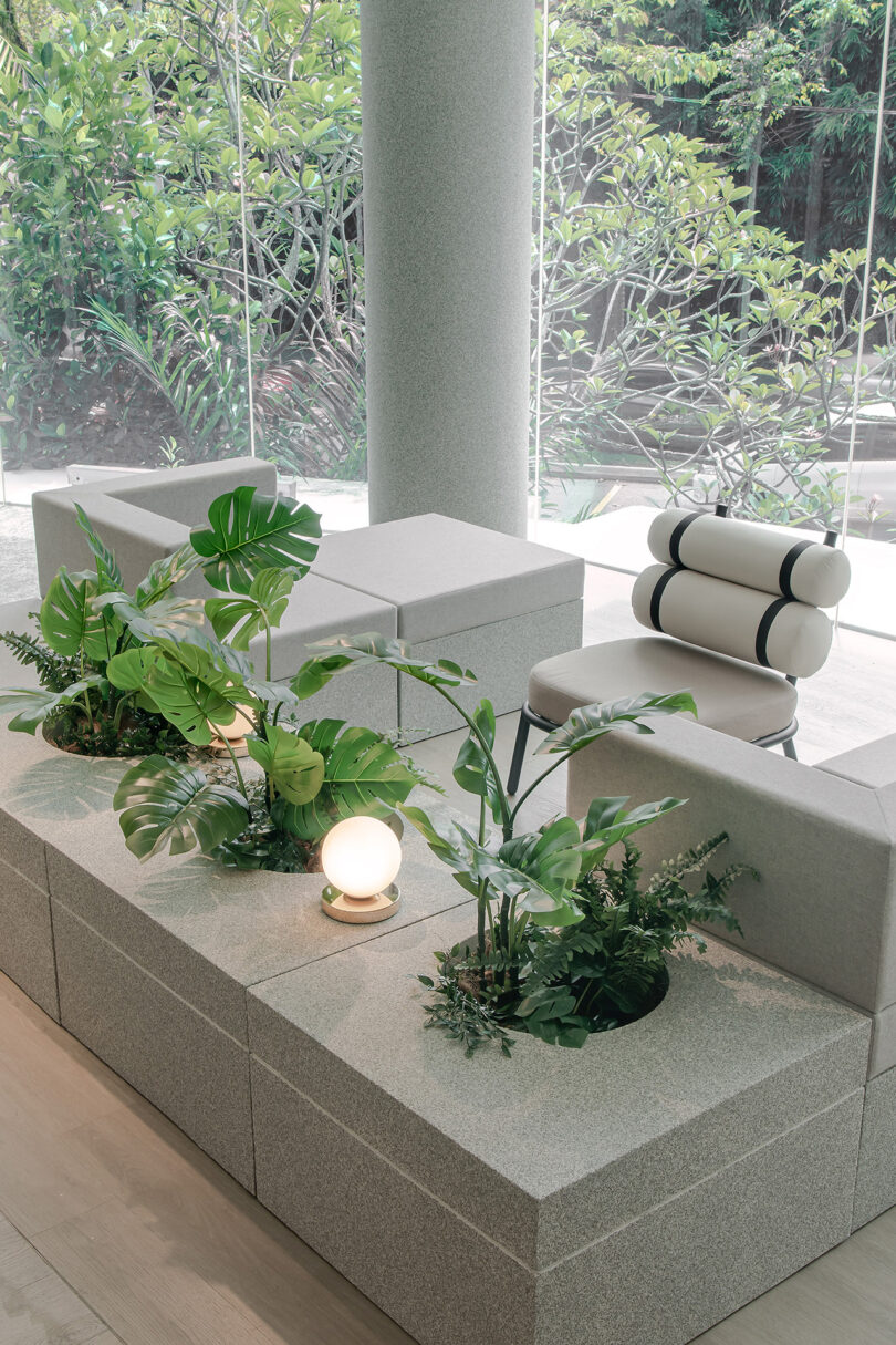 interior commercial lounge space with white furniture, large windows, and greenery