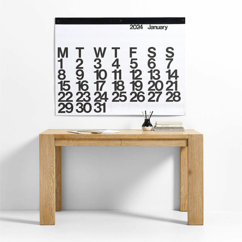 large black and white Stendig wall calendar hanging above simple wood console table