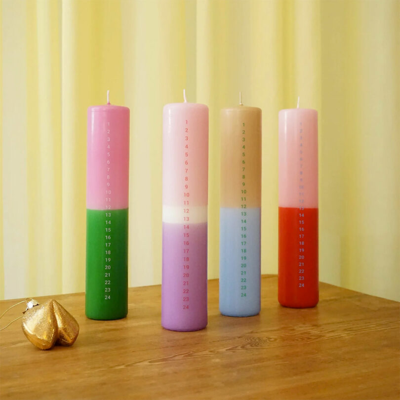 four two-tone pillar candles with dates down front marking december