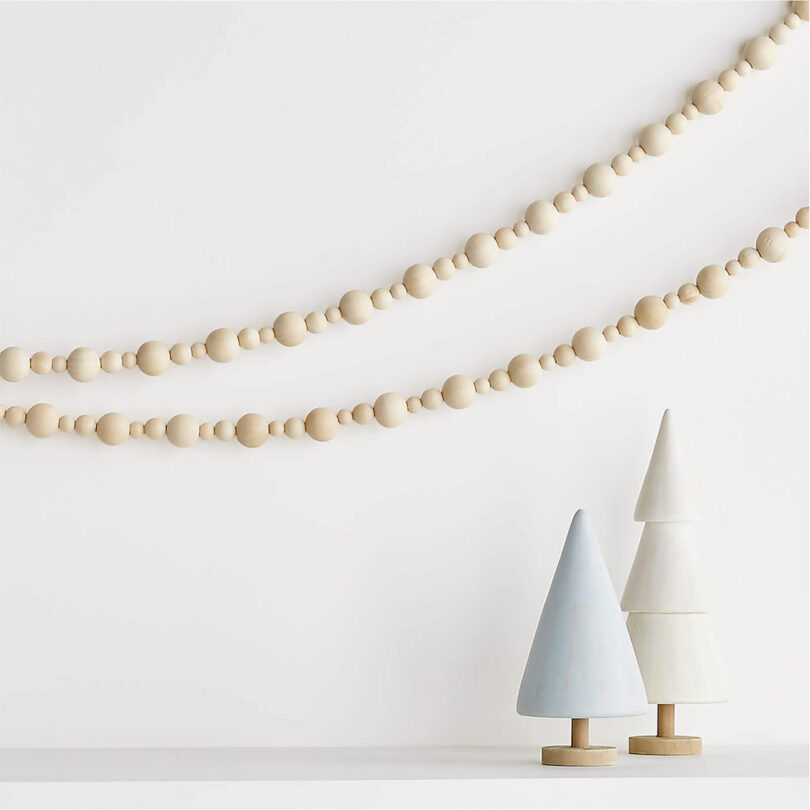 two strands of wood beaded garland hanging above two christmas trees