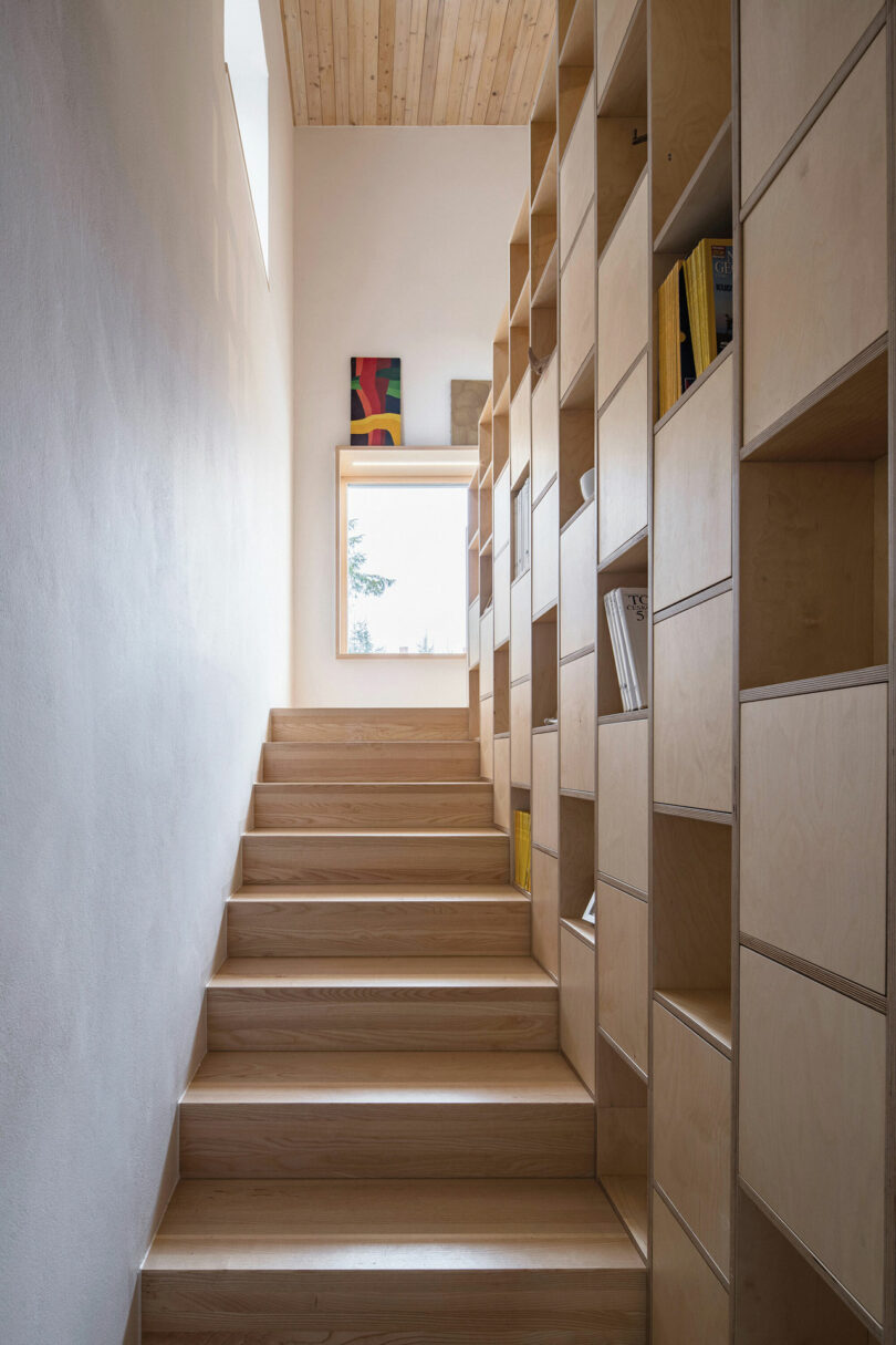 looking up wood staircase with one side of open and closed bookshelves