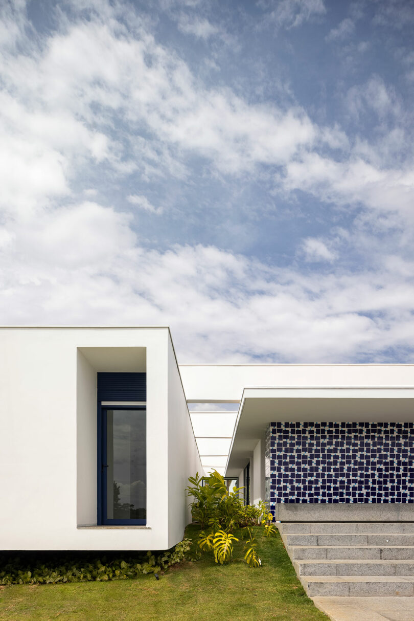 closeup exterior view of modern white rectilinear house with geometric blue and white tile wall