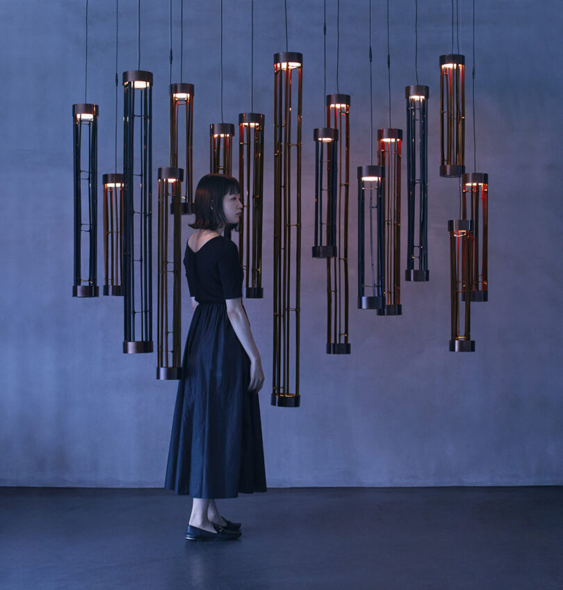 woman in black dress stands in front of large statement lighting