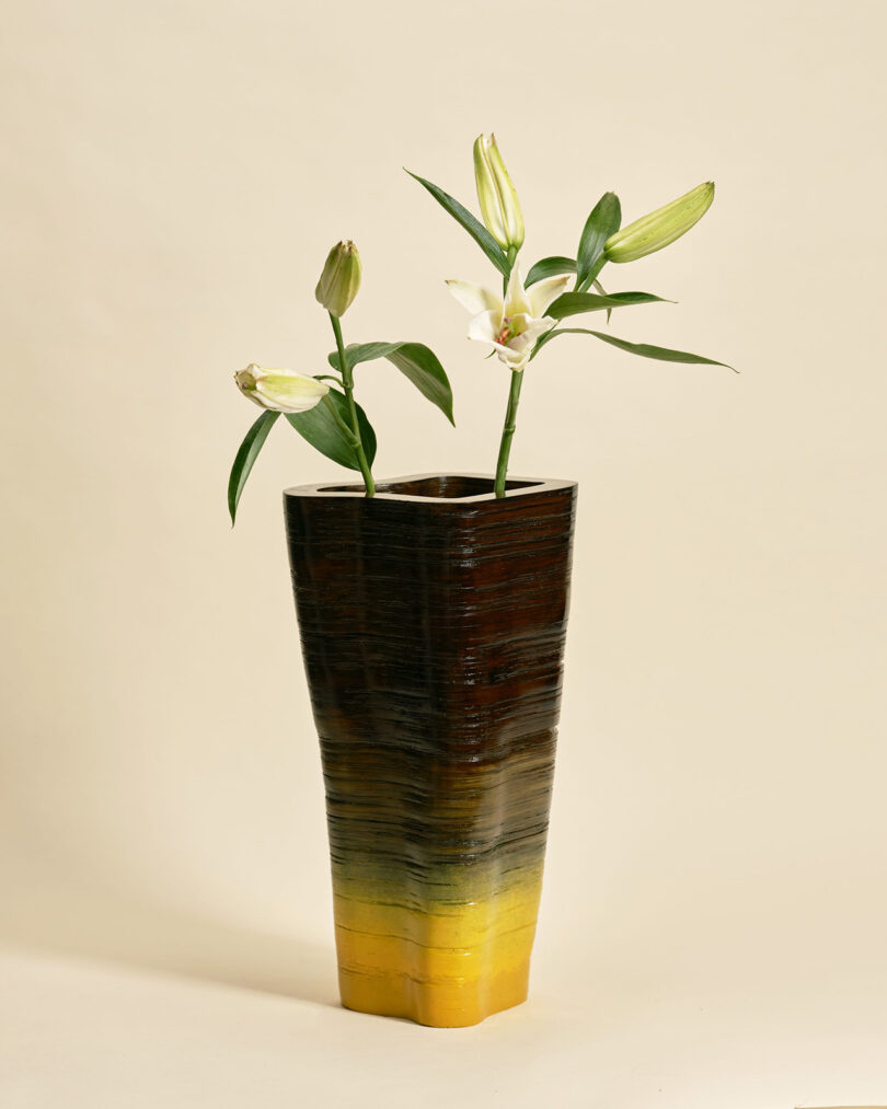 tall vase with a yellow and black gradiation holding greenery