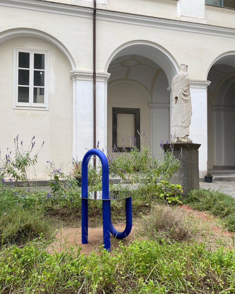 graphically shaped blue and mirrored side table outside a white building