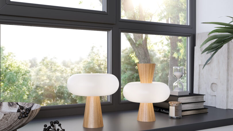 two white and wood table lamps on black desk next to window