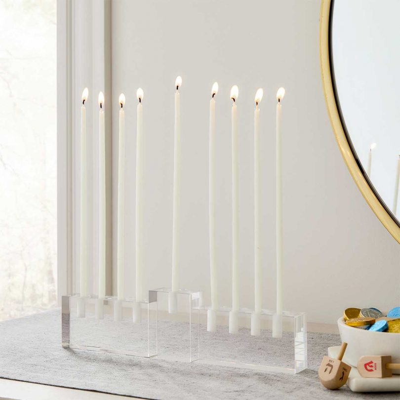 glass menorah on table with white candles lit