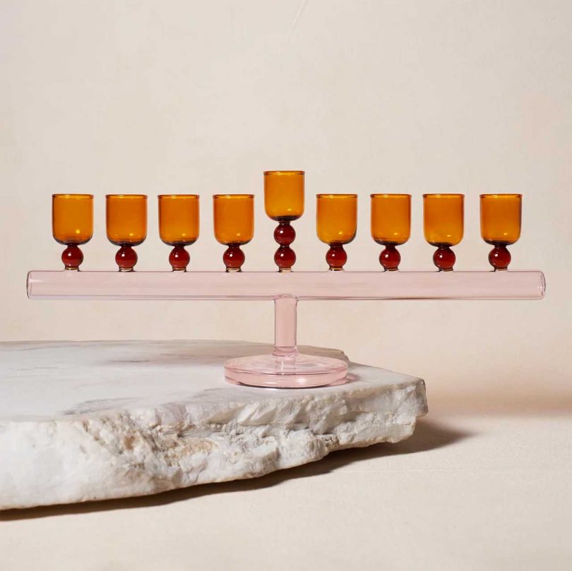 pale pink and amber glass menorah on a stone
