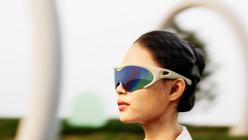 Young woman with hair put up in a bun wearing Morrama Issé Mixed Reality Glasses with blurred background implying movement.