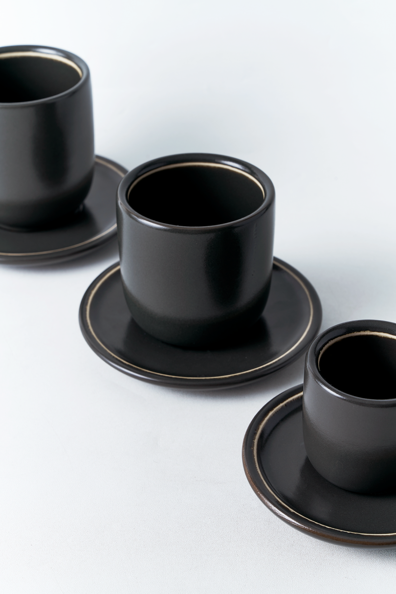 three black mugs and saucers