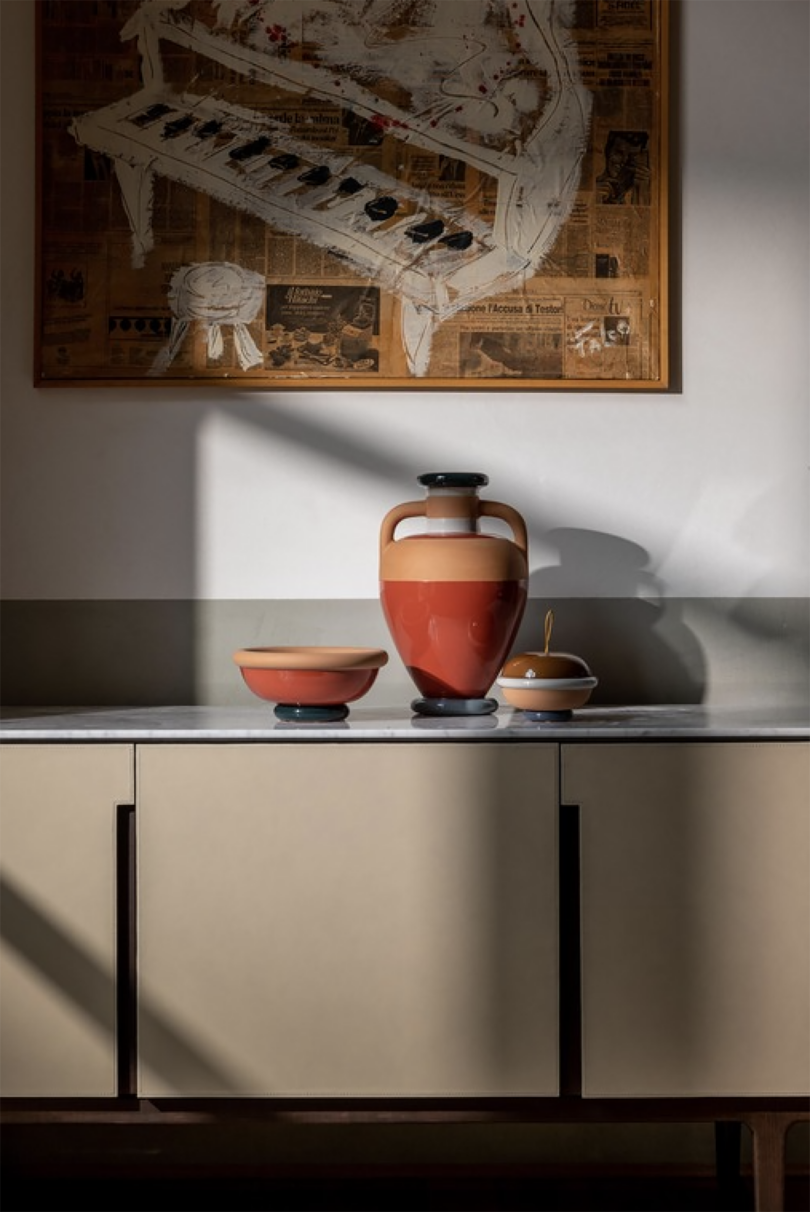 deep orange and light brown ceramic vase, bowl, and cup on a wood surface